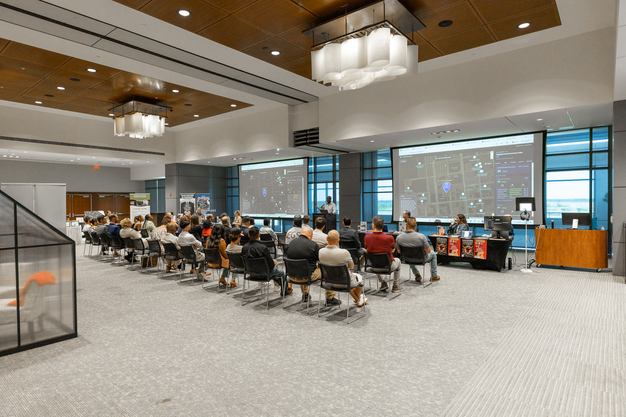 NEX Connect event — audience seated facing two screens showing the Newkirklytics OS map